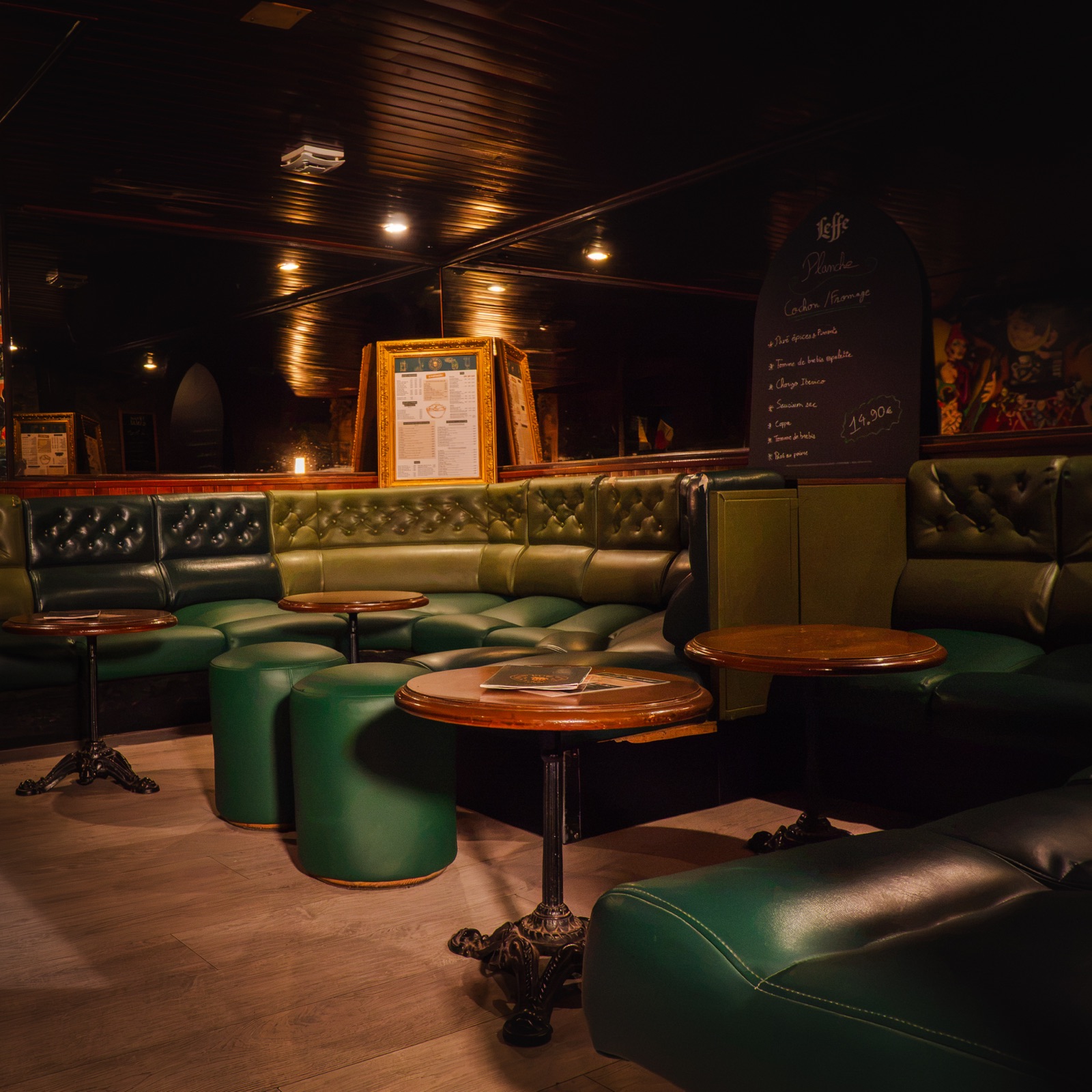 Salon du pub avec banquettes en cuir vert et petites tables